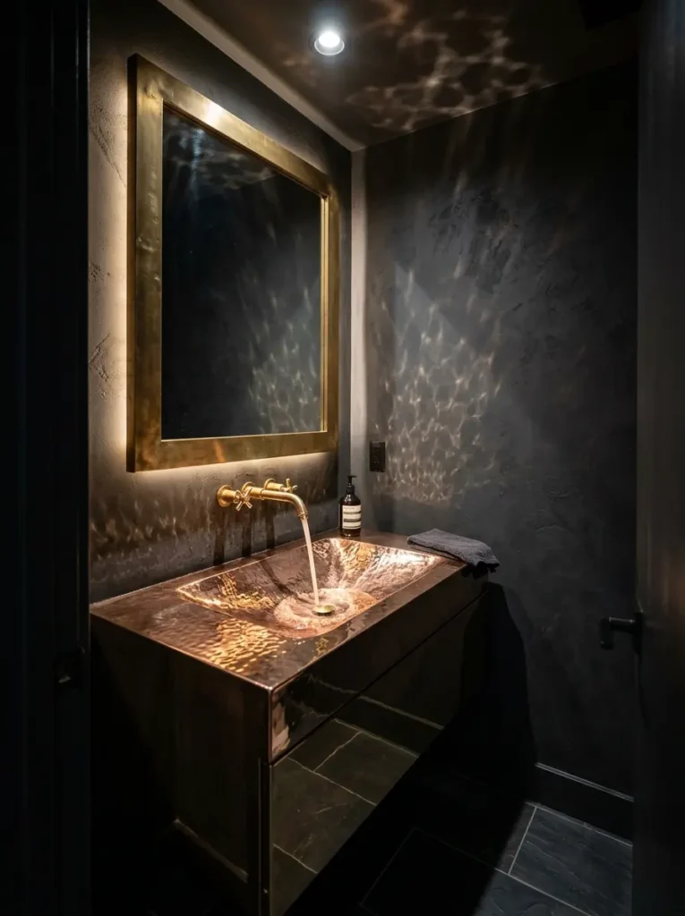 Reflective Copper Bathroom Sink Hammered copper sink basin reflecting light inside a dark charcoal powder room.