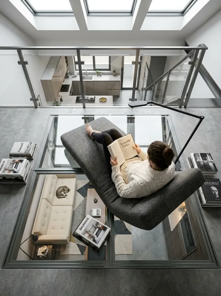 Glass Floor Loft Woman reading on a grey chair placed on a glass floor loft.