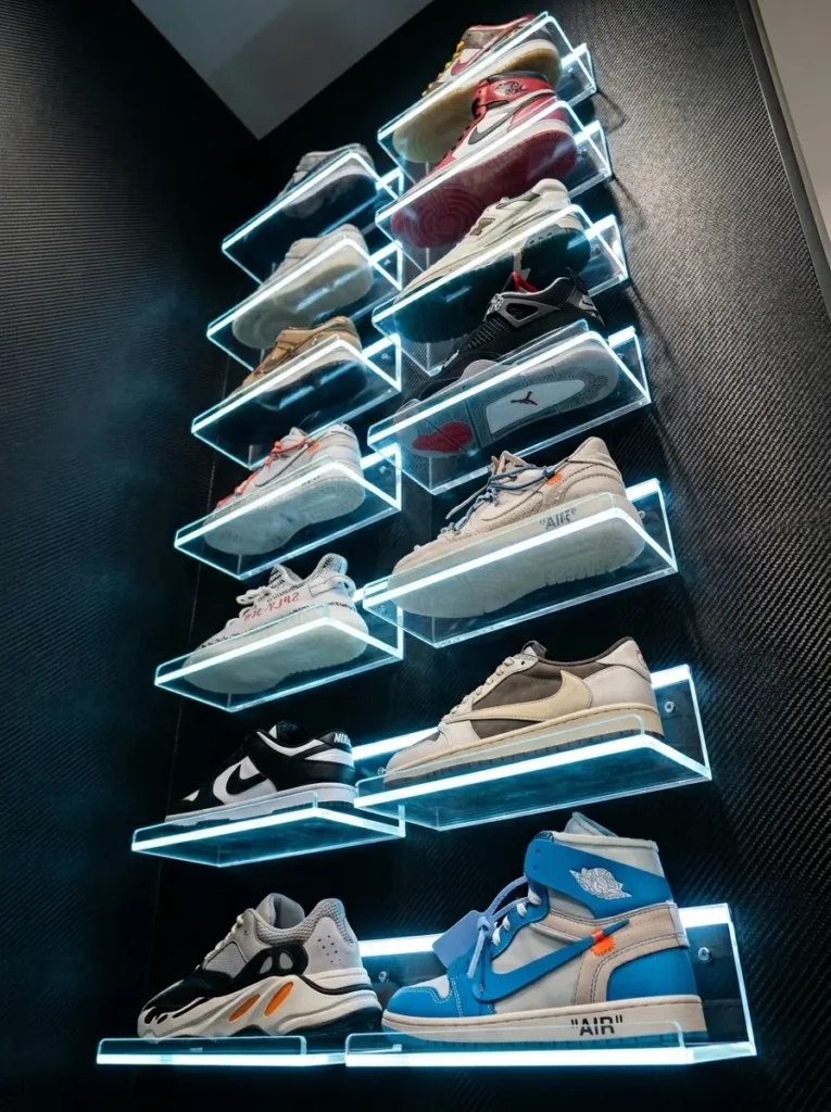 Clear acrylic angled wall ledges edged with blue LED light holding a collection of rare sneakers.
