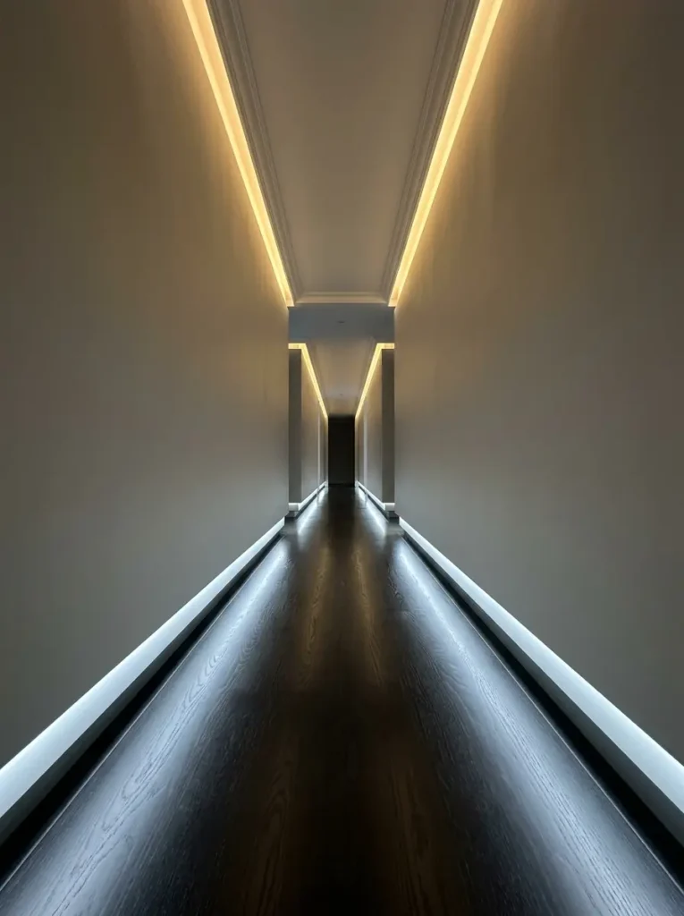 Hidden LED light strips glow from the recessed baseboards in a hallway