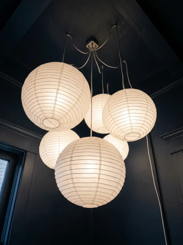 Five white paper lantern globes clustered together on a dark bedroom ceiling