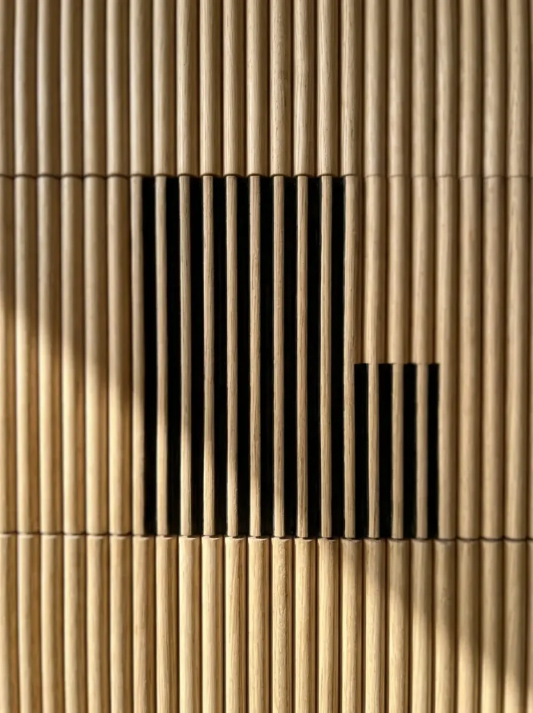 Lower half of a bedroom wall covered in thin vertical blonde pine dowels creating ribbed texture.