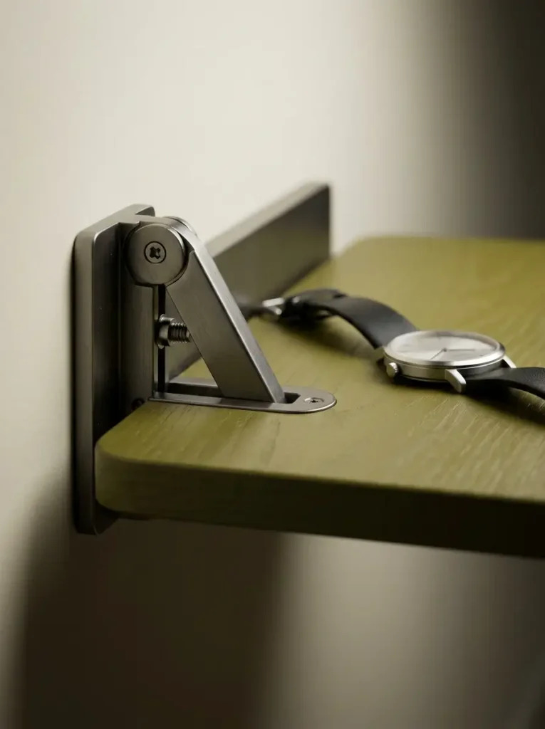 Small wall-mounted foldable wooden shelf supporting a watch.