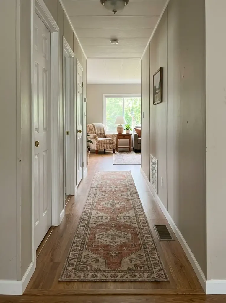 Long mobile home hallway with a muted rust and oatmeal runner centered between clear floor margins