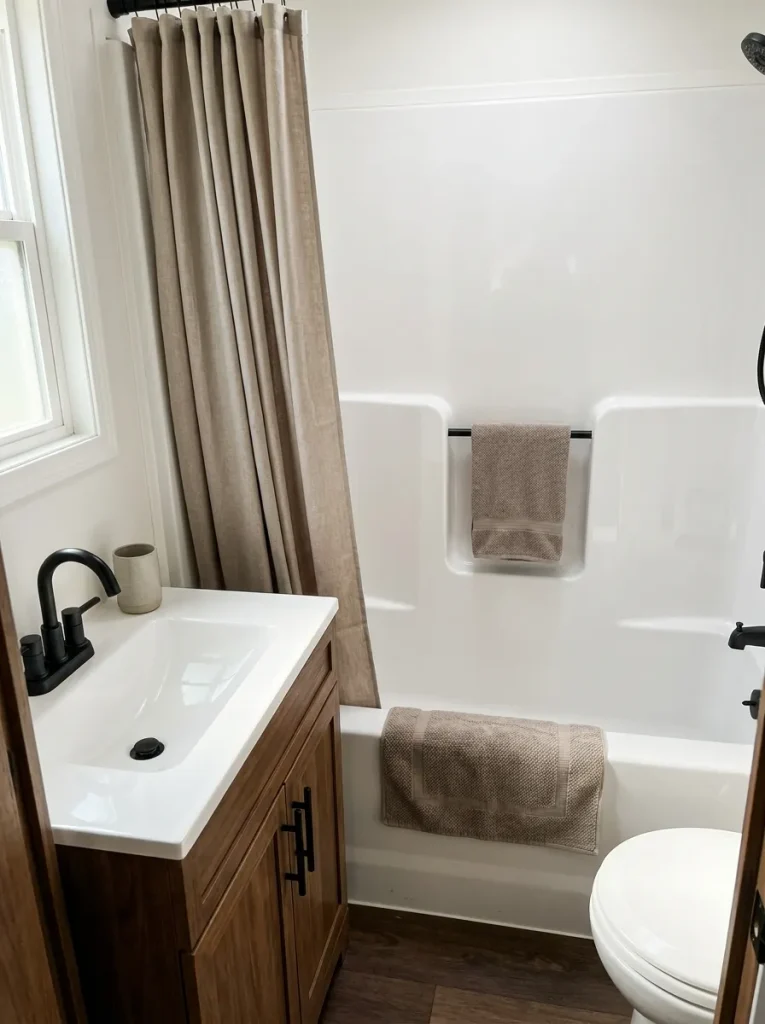 White sink and tub visually connected to walnut cabinetry and black hardware with mushroom and flax neutral accents.