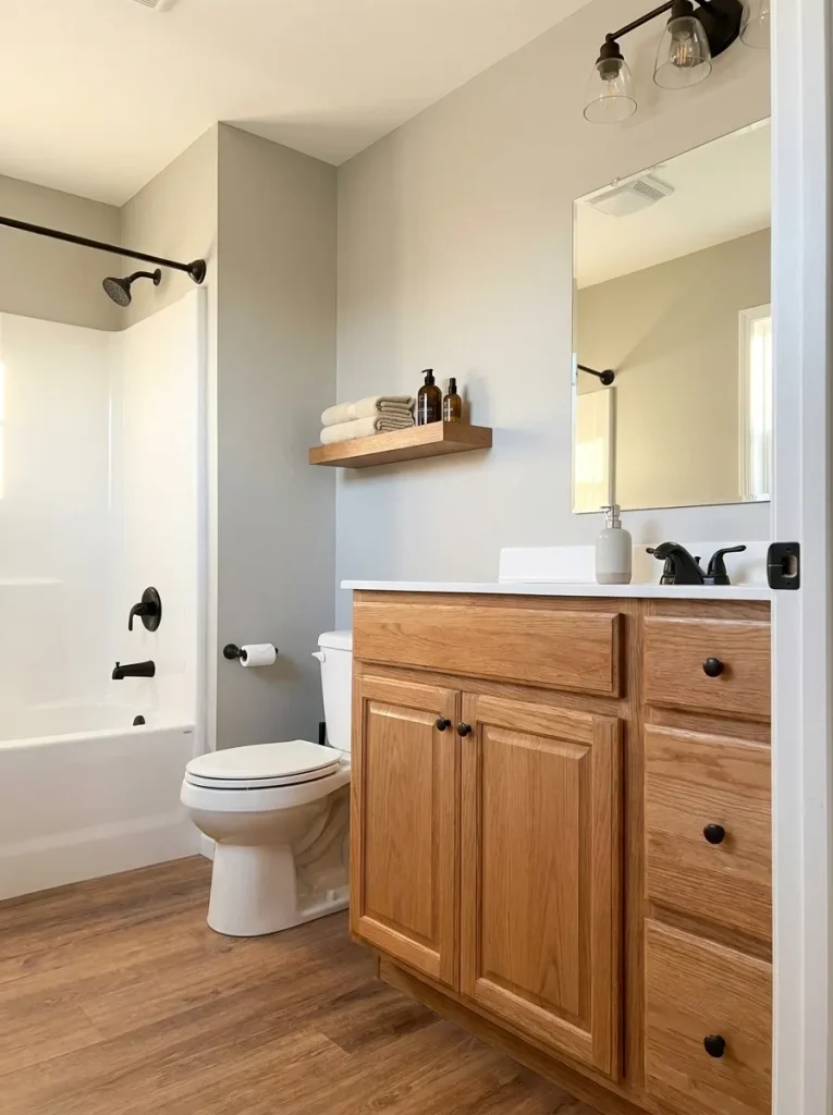 Warm wood vanity acting as the main material anchor in a compact mobile home bathroom.