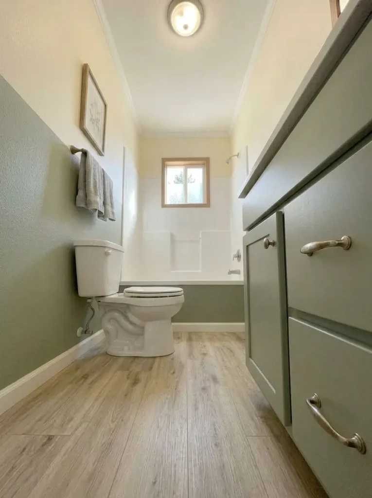 Partially screened bathroom window preserving daylight across the tub and floor of a narrow single-wide bathroom.