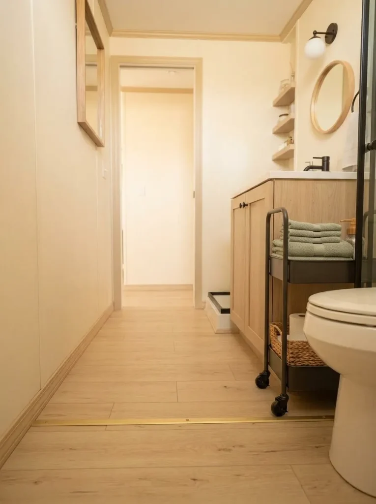 Slim rolling bathroom cart parked neatly beside a vanity without blocking the compact room's walking route.