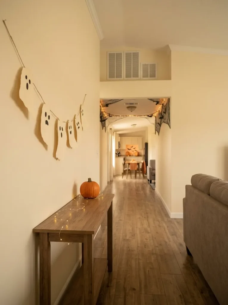 Short torn-paper ghost garland above a narrow console in a warm neutral mobile home entry.