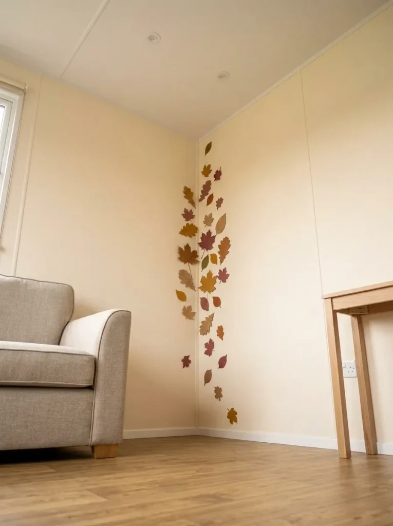 Felt autumn leaves cascading beside an inside wall corner in a compact mobile home while the architectural seam remains visible.