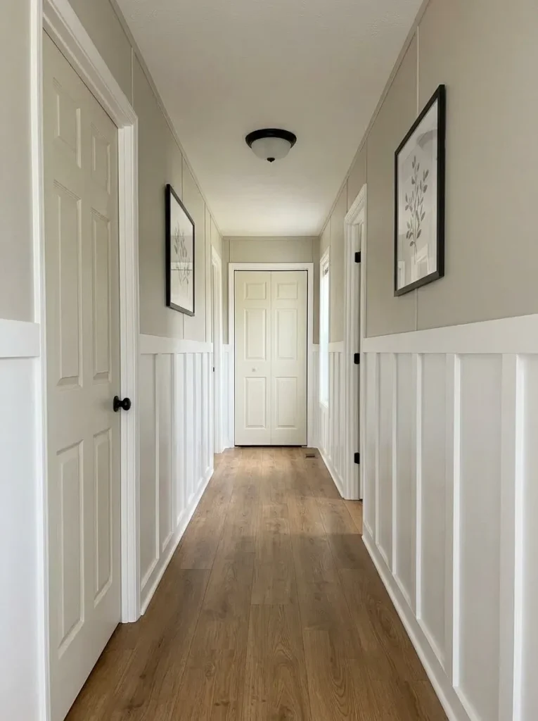 Narrow mobile home hallway with half-height white board-and-batten below warm gray upper walls and a clear central walking route.