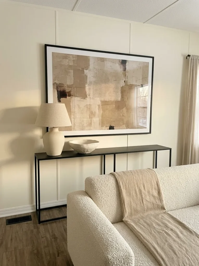 Mobile home living room with one large wall-art anchor, a substantial lamp and fewer small décor pieces.