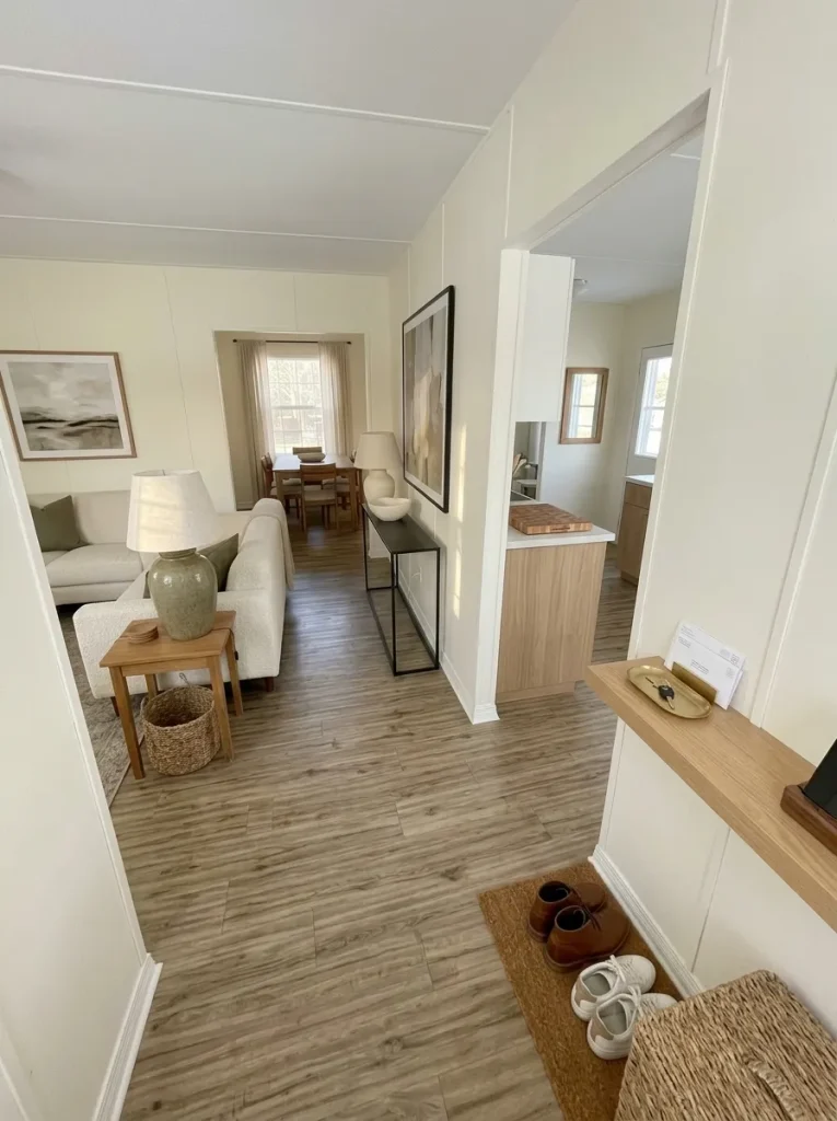 Connected mobile home interior repeating warm wood accents across the living room, dining area and kitchen.