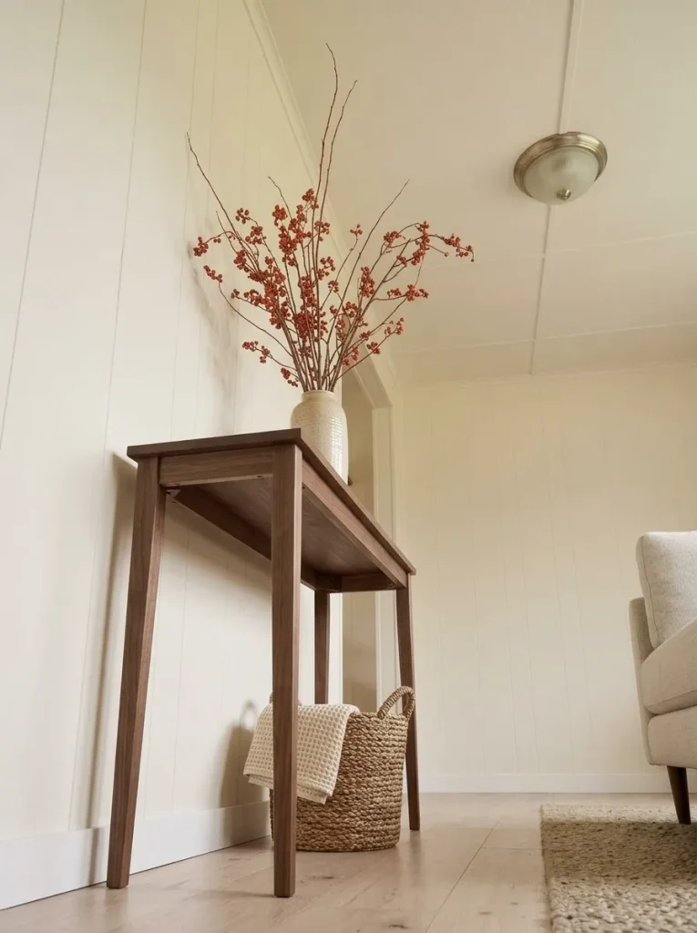 Tall Persimmon autumn branches in a ceramic vase add vertical fall color above a narrow mobile home console.