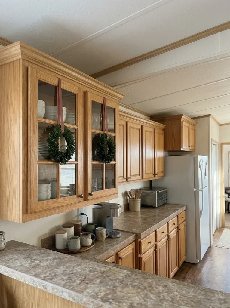 Staggered upper cabinets in a mobile home kitchen with selected wreaths visually balanced at different door heights.