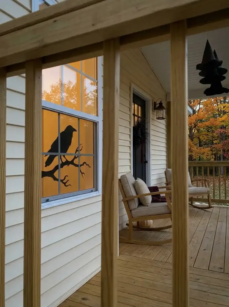 Large raven silhouette behind a front window visually extends a Halloween mobile home porch without using additional landing space.