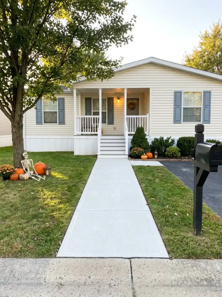 Clear concrete walkway through a Halloween-decorated mobile home front yard with props kept safely to the lawn and planting edges.