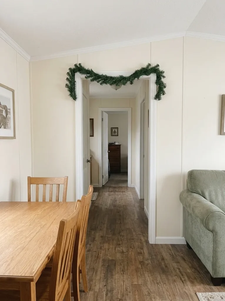Unlit evergreen garland dry-fitted along the fixed upper trim of a mobile home doorway with a clear passage beneath.