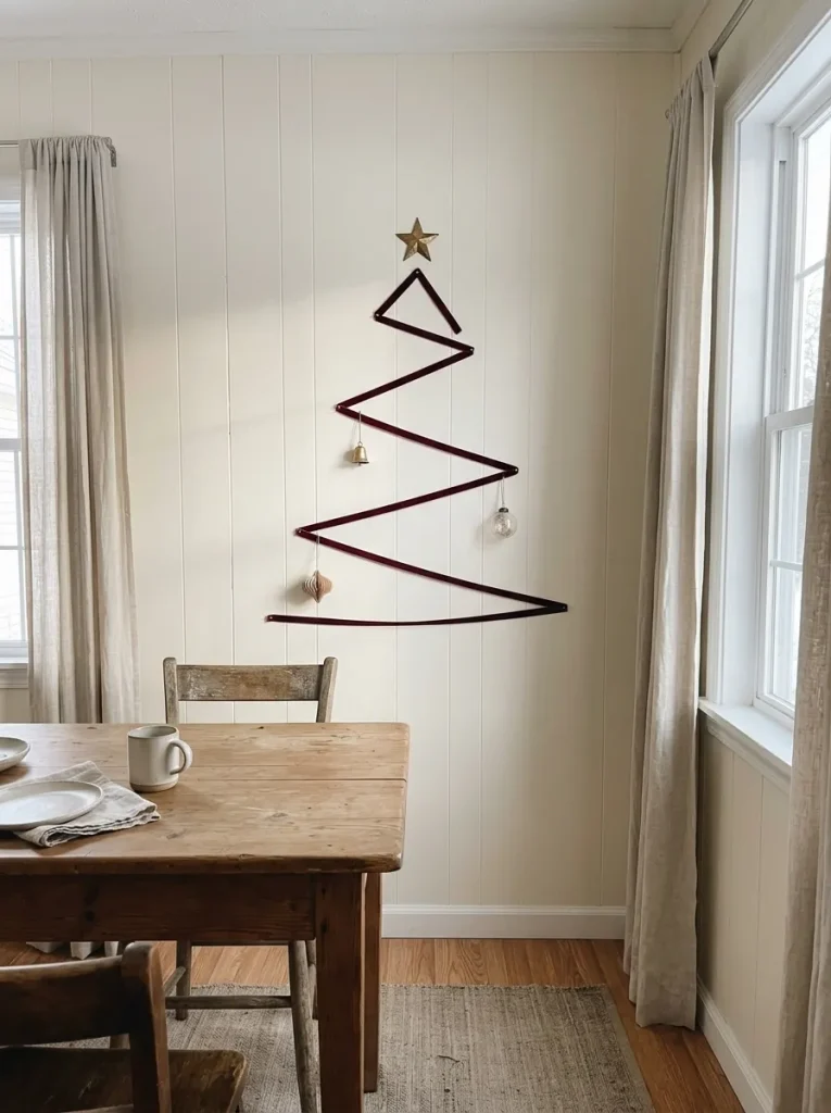 Burgundy velvet ribbon outlining a flat Christmas tree beside a small manufactured-home dining nook.