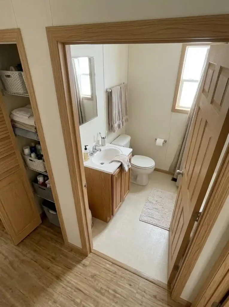 Compact single-wide bathroom with only daily supplies inside while reserve toiletries and linens are stored in a nearby hall cabinet.