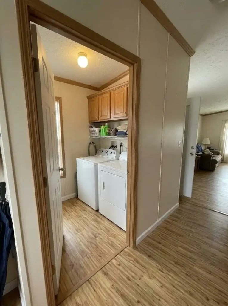 Single-wide laundry area with upper storage above the washer and dryer and clear floor space beside the appliances.
