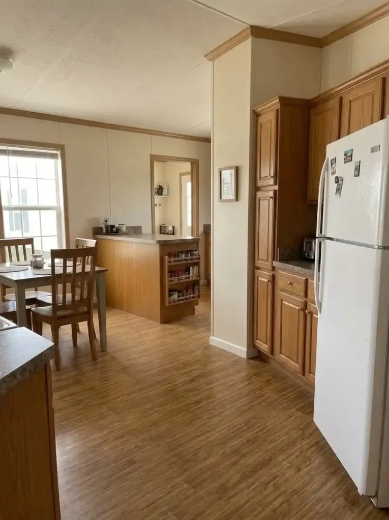 Single-wide kitchen with refrigerator and tall pantry followed by a landing counter and an open visual break.