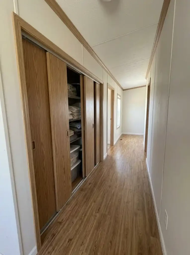 Sliding-door cabinet along a narrow single-wide passage with the walkway remaining open while the storage is accessed.