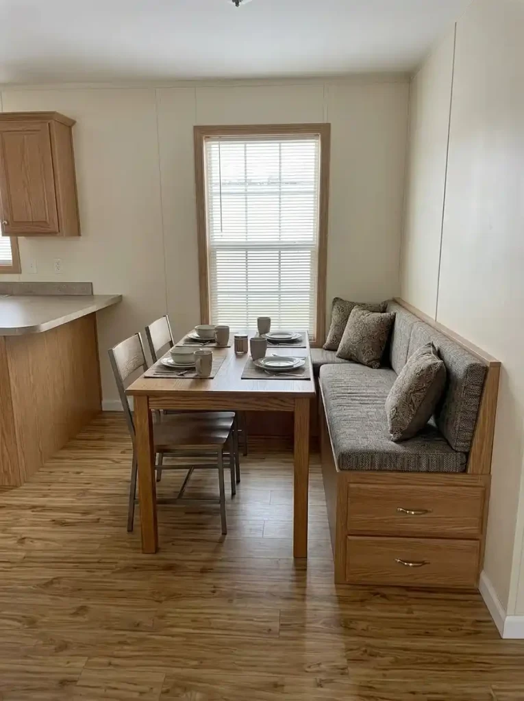 Storage banquette replacing dining chairs and a separate cabinet in a compact single-wide dining nook.