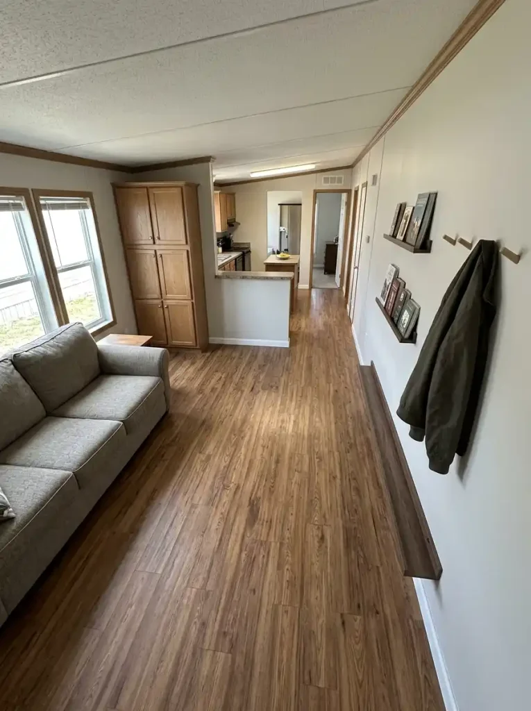 Single-wide interior showing a clear center route, shallow storage along a long wall and deeper cabinetry on an end wall.