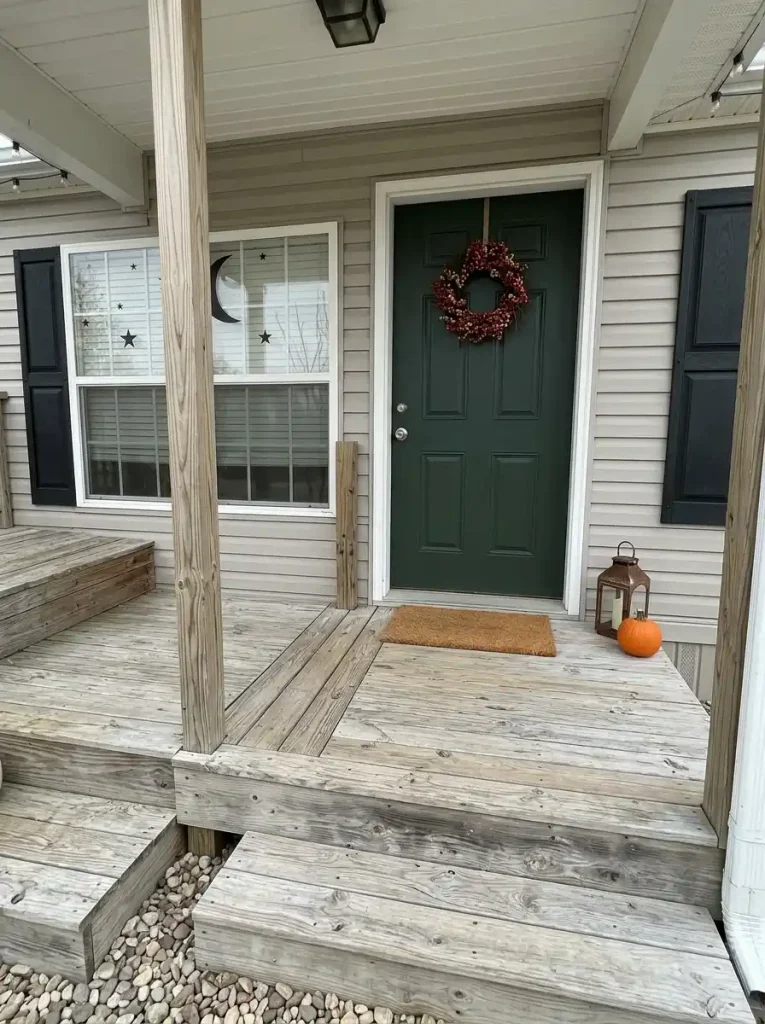 Compact manufactured-home entry with one Halloween mat and a single edge accent leaving the door swing and arrival space clear.